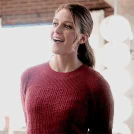 a woman in a red sweater is standing in front of a window .