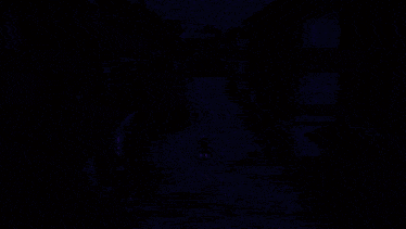 a man in a blue shirt is walking down a dirt road