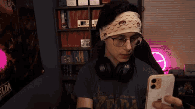 a man wearing headphones and a headband is looking at his phone .