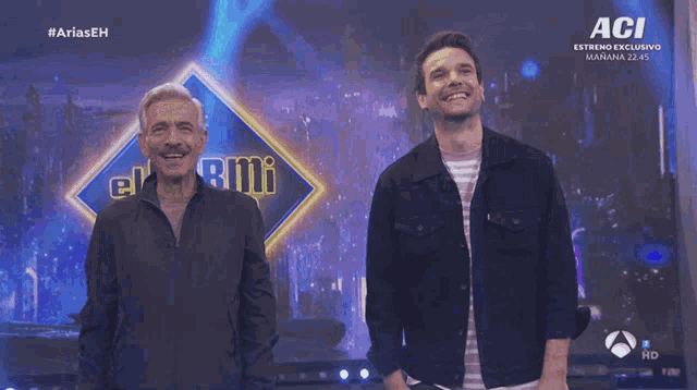 two men standing in front of a sign that says el armi