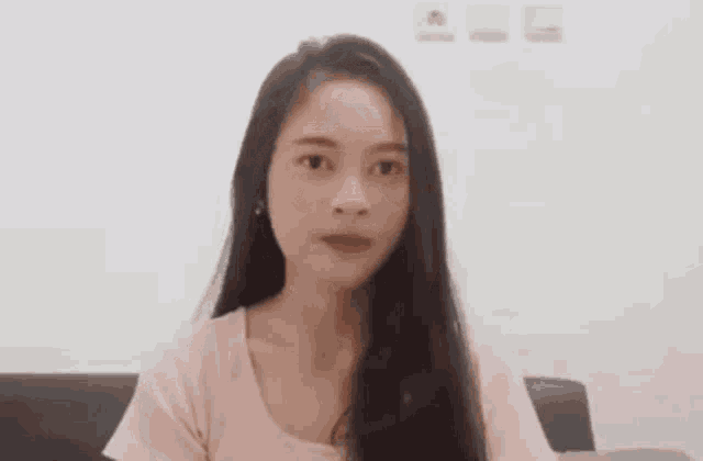 a woman with long hair is sitting on a couch and making a face .