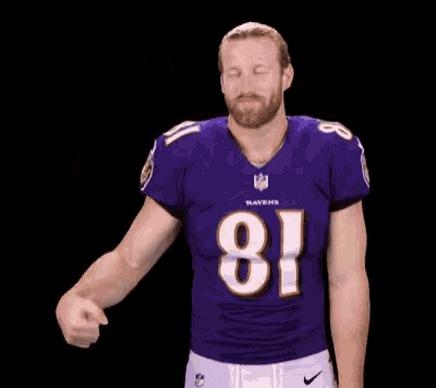 a man in a ravens jersey is flexing his arm