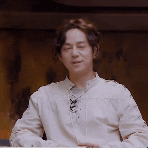a man is sitting at a table with his eyes closed .