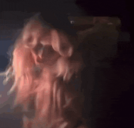 a blurry picture of a woman with pink hair in a dark room .
