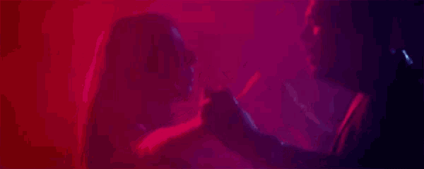 a man and a woman are holding hands in a dark room with red and blue lights .