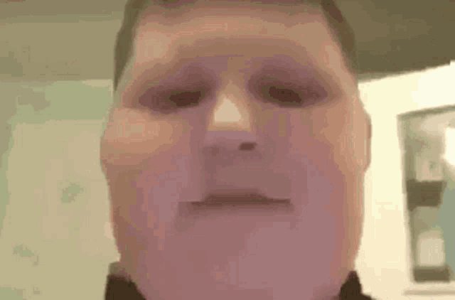 a close up of a man 's face making a funny face while looking at the camera .