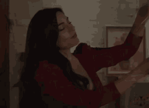 a woman in a red dress is standing in a room with her hands outstretched .