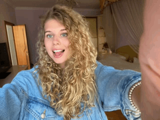 a woman in a denim jacket is taking a selfie
