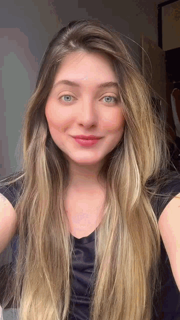 a woman with long blonde hair wearing a black shirt