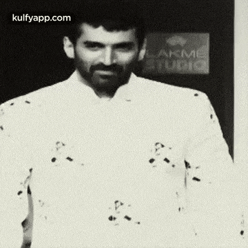 a man with a beard is wearing a white shirt and smiling .