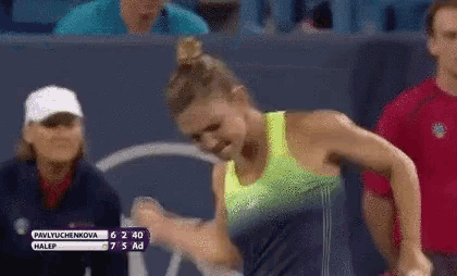 a woman in a yellow tank top is holding a tennis racquet while playing tennis .