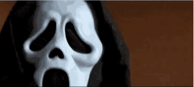 a close up of a scream mask with its mouth open and a hood .