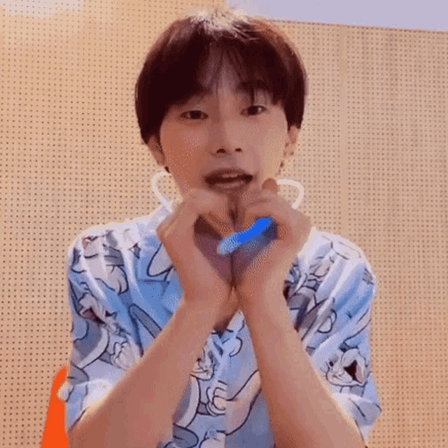 a young man in a blue shirt is making a heart with his hands .