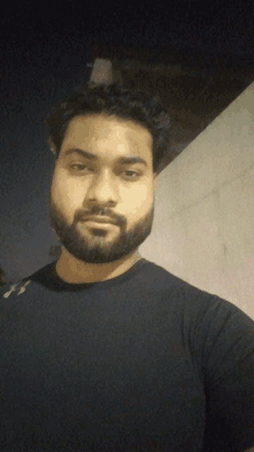 a man with a beard is wearing a black shirt that says ' x ' on the front