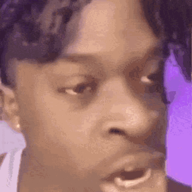 a close up of a person 's face with their mouth open and a purple background .