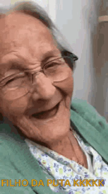 an elderly woman wearing glasses and a green sweater is laughing and smiling .