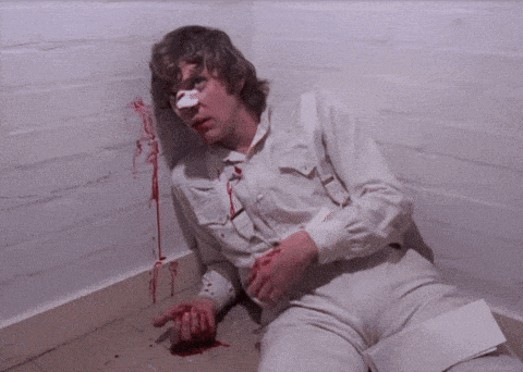 a man with a bandage on his nose is laying on the floor with blood coming out of his nose