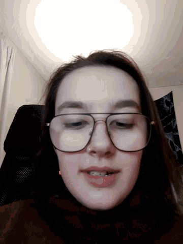 a woman wearing glasses looks at the camera with a smile on her face