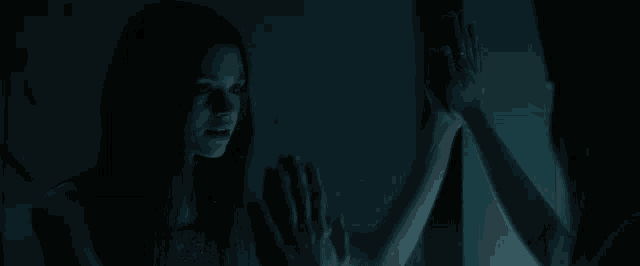 a woman looking at herself in a mirror with her hands on the glass