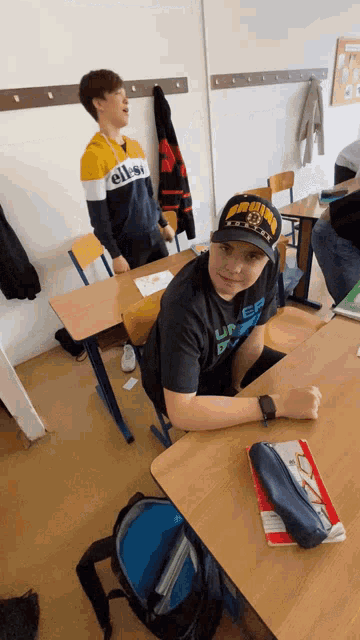 a boy wearing an ellesse sweatshirt sits at his desk