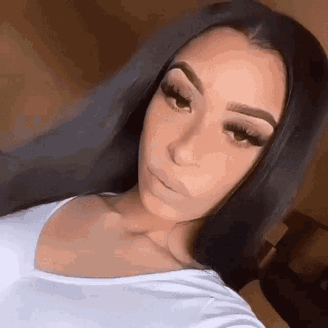 a woman with long black hair is taking a selfie in a white shirt .