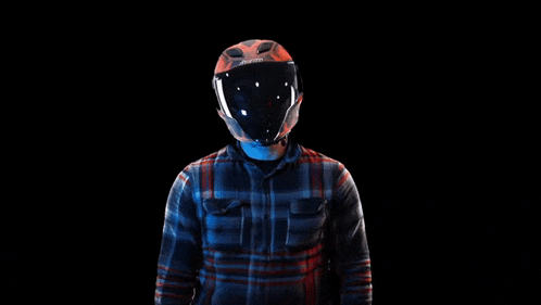 a man wearing a helmet and a plaid shirt is holding his hands up in the air