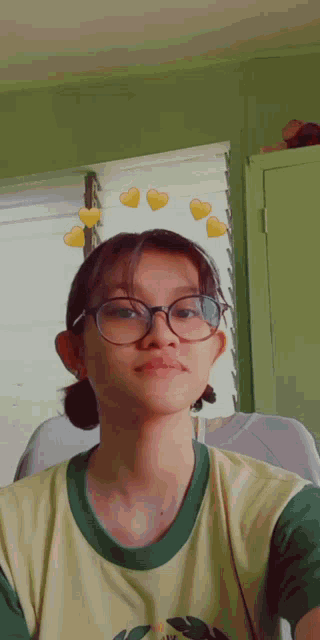 a girl wearing glasses is taking a selfie in front of a window .