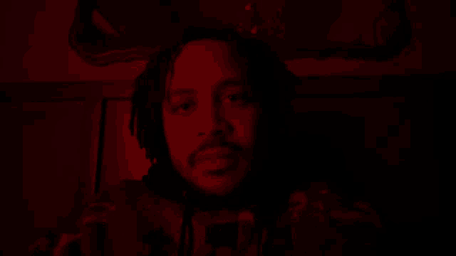 a man with dreadlocks and a beard is in a red light