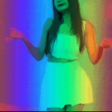 a woman in a white dress is dancing in front of a rainbow colored background .