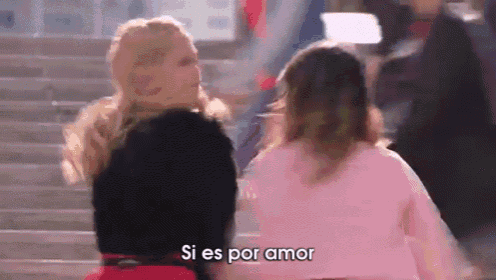 two women are standing next to each other on a set of stairs and one of them is talking in spanish .
