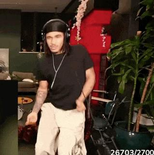 a man wearing headphones and a bandana is dancing in a living room ..