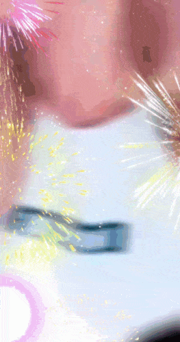 a close up of a person 's face with fireworks behind it