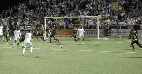 a group of soccer players are playing on a field with a gates sign in the background
