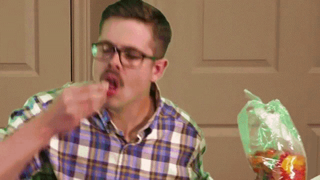 a man in a plaid shirt is eating gummy bears from a bag