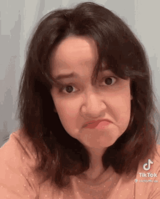 a woman is making a funny face with her mouth open and looking at the camera .