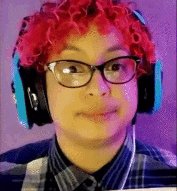 a young man with red curly hair and glasses wearing headphones