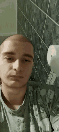 a man with a shaved head is wearing a grey shirt