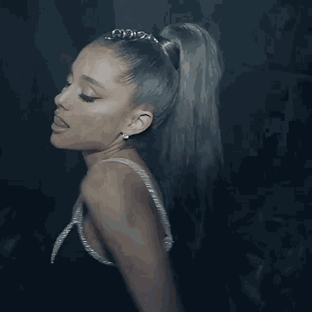 ariana grande is wearing a black dress and a ponytail in a video .