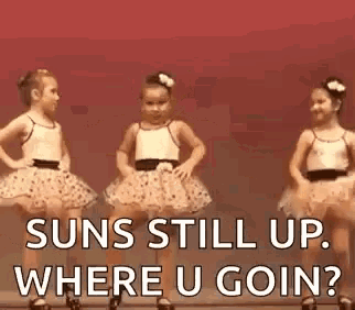three little girls in tutus are dancing on a stage with the words `` suns still up where u goin '' .