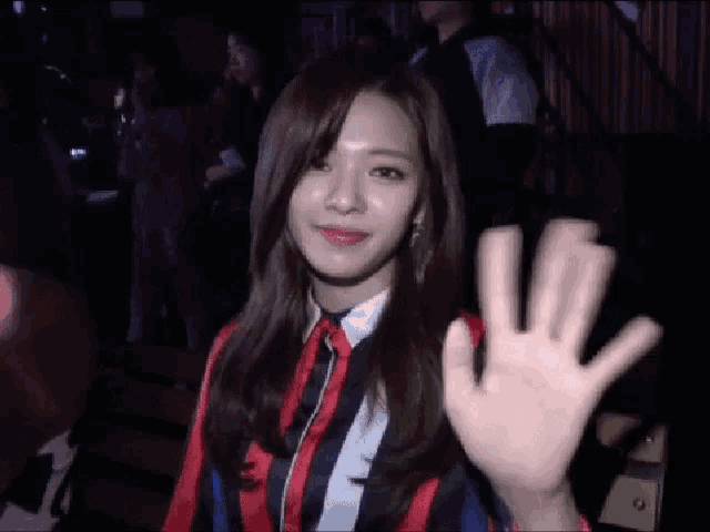 a woman in a striped shirt is waving her hand in a crowd .