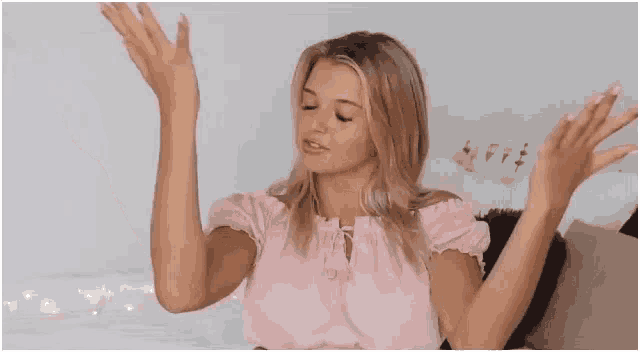 a woman is sitting on a bed with her arms outstretched .