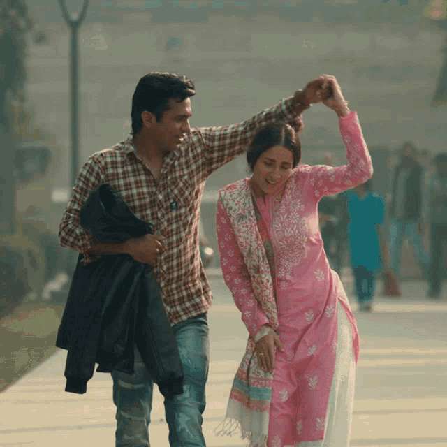 a man in a plaid shirt is holding a woman in a pink dress