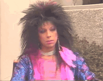 a woman wearing a wig and a pink and blue shirt