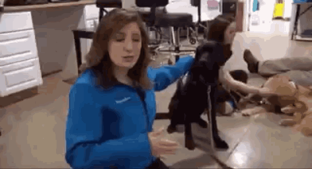 a woman in a blue jacket is standing next to a dog