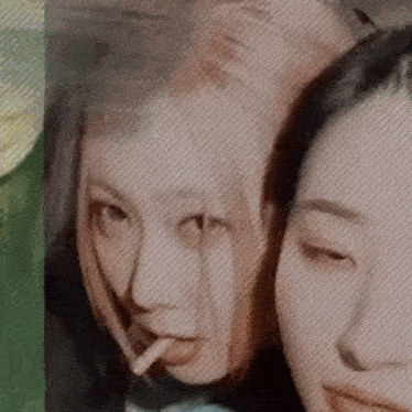 a close up of two women 's faces with one smoking a cigarette .