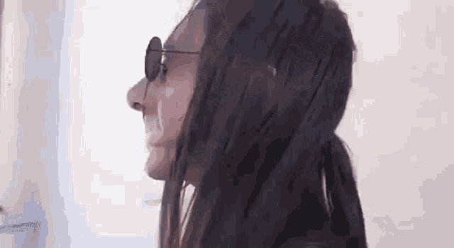 a woman wearing sunglasses and a ponytail is looking at something .