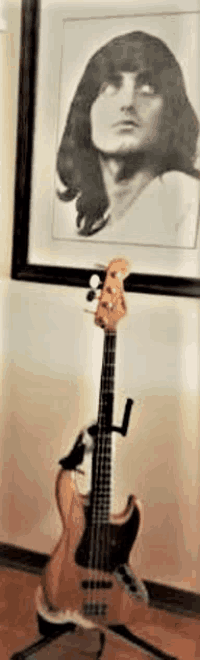a bass guitar is sitting on a stand in front of a picture of a man .