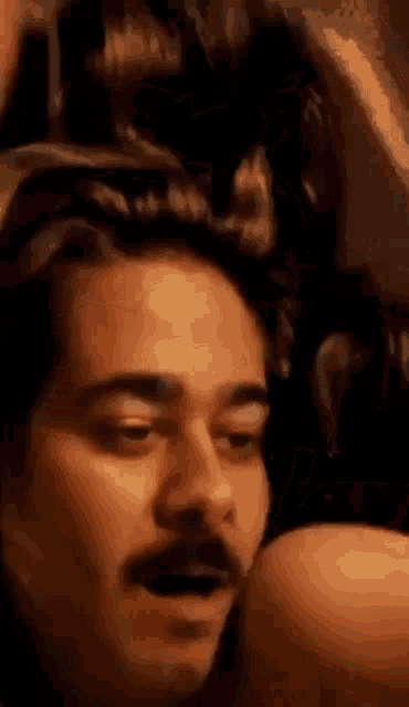 a man with a mustache is holding a woman 's head .