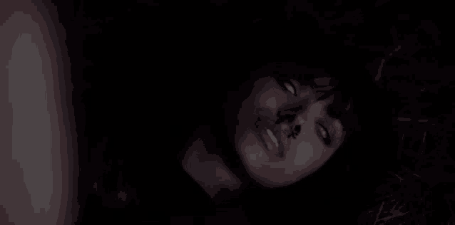 a woman with a bloody nose is laying on the ground in the dark .