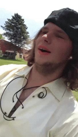 a man wearing a black hat and a white shirt is laughing